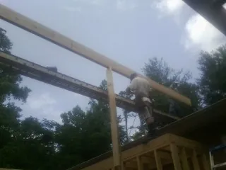 Carpenter setting a ridge beam over a new addition frame — Ice Dam Removal by Roofing Brothers in Lowell